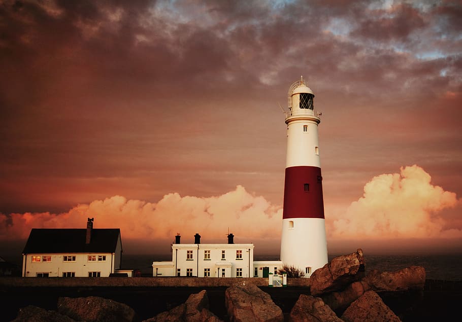 lighthouse on cliff with clouds in background, portland bill