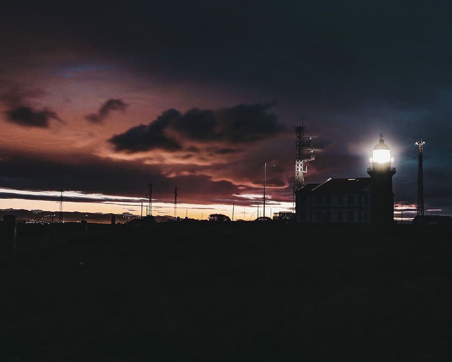black lighthouse under brown and black sky, turned-on black street lamp HD wallpaper