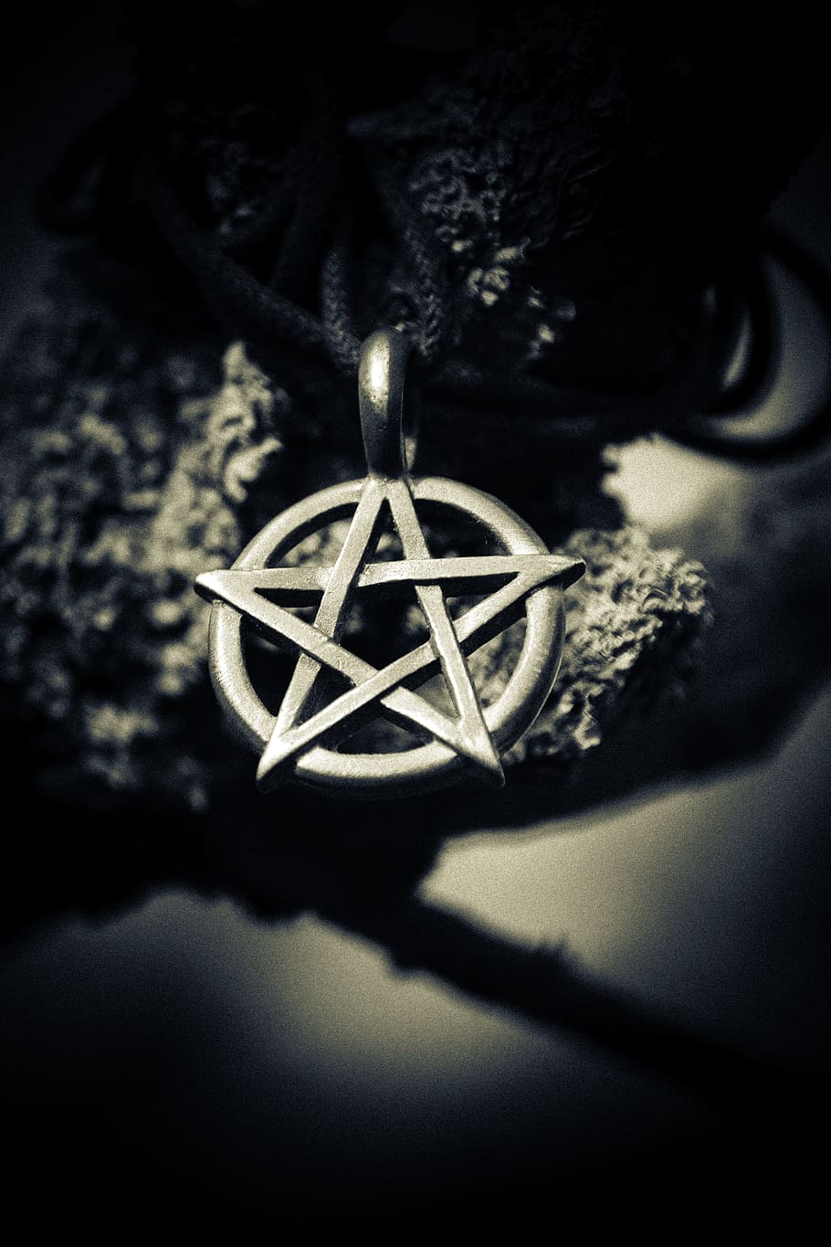 grayscale depth of field photography of star pendant, silver star