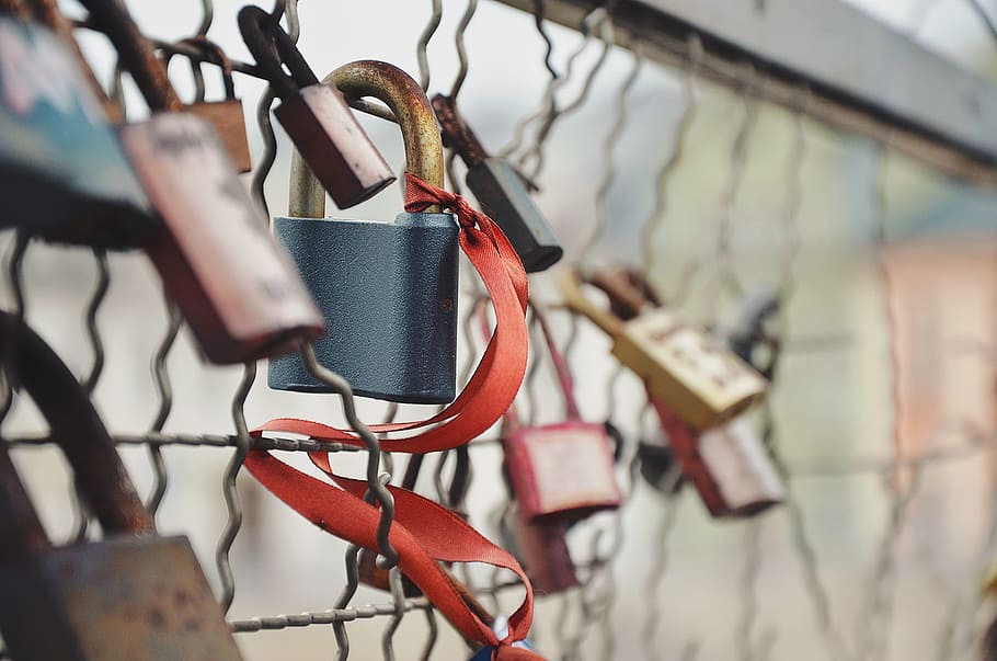 selective focus photography of padlock on chain link fence, Lovelock Bridge padlock with red ribbon in closeup shot