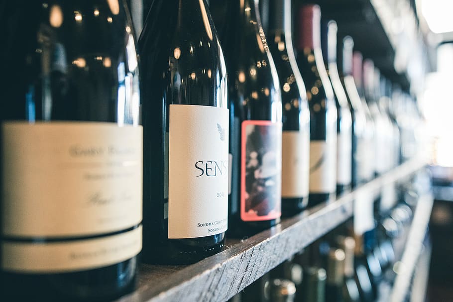 organized bottles on shelf, black bottle lot on wooden rack, wine
