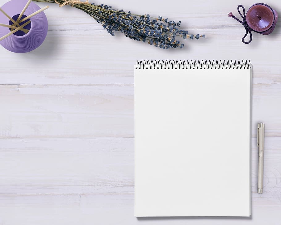 white notebook with gray ballpoint pen, notepad, table, flowers