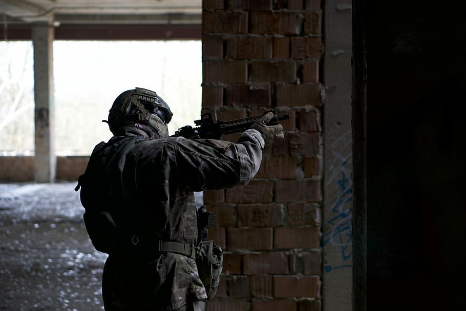 man holding rifle beside wall, person holding rifle, building HD wallpaper