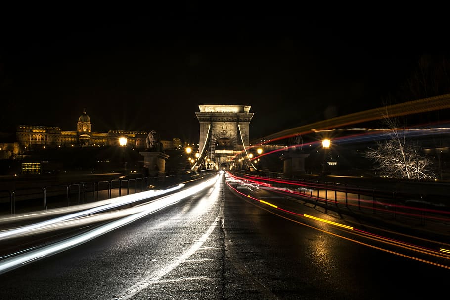 timelapse photography of vehicle lights near buildings, chain bridge