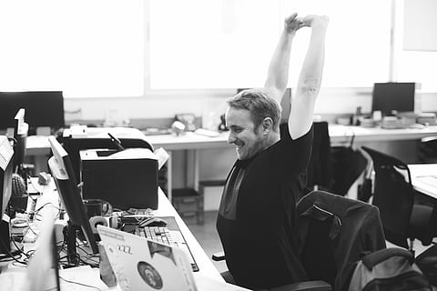 Well-deserved break, grayscale photo of man stretching arms in front of computer HD wallpaper