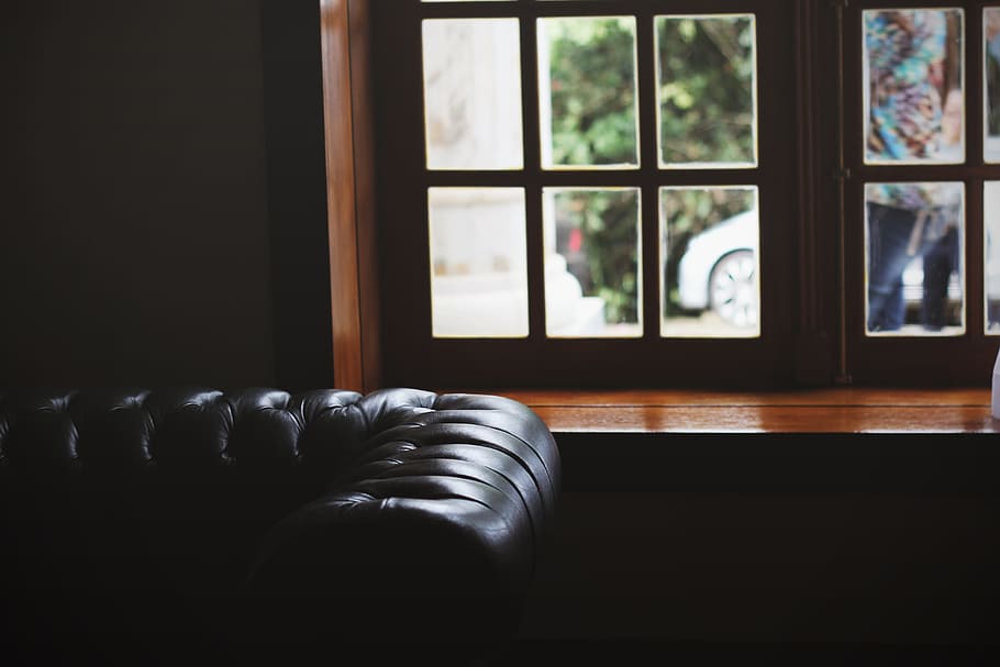 leather brown couch, tufted black leather sofa near brown wooden framed window inside the room