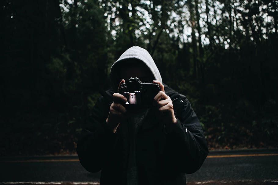 person wearing hoodie holding camera near road and forest, people, HD wallpaper
