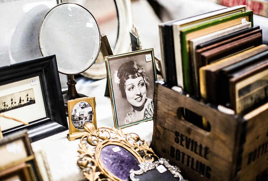 collection of books on brown wooden crate, books beside photo frames and mirror on white surface HD wallpaper