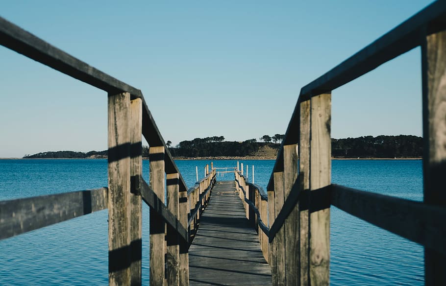 empty brown wooden sea dock under blue sky, brown wooden dock on body of water near mountain HD wallpaper