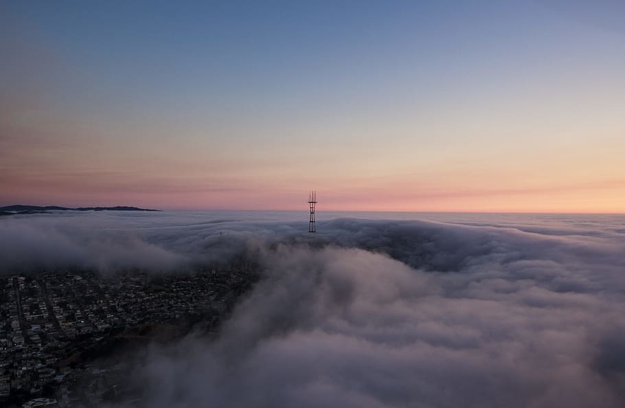 tower surrounded by clouds, aerial photograph of a city under orange cloudy skies HD wallpaper