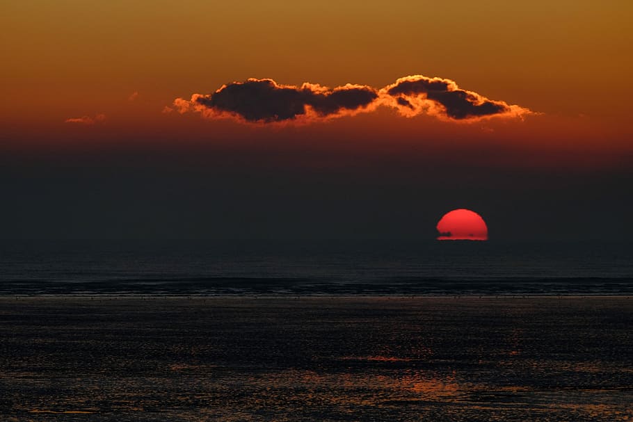 sun setting on body of water, orange and black clouds over calm body of water HD wallpaper