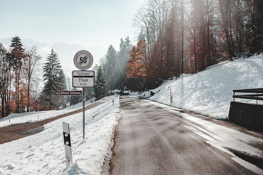 road covered by snow near to mountain, road sign near road during winter season HD wallpaper