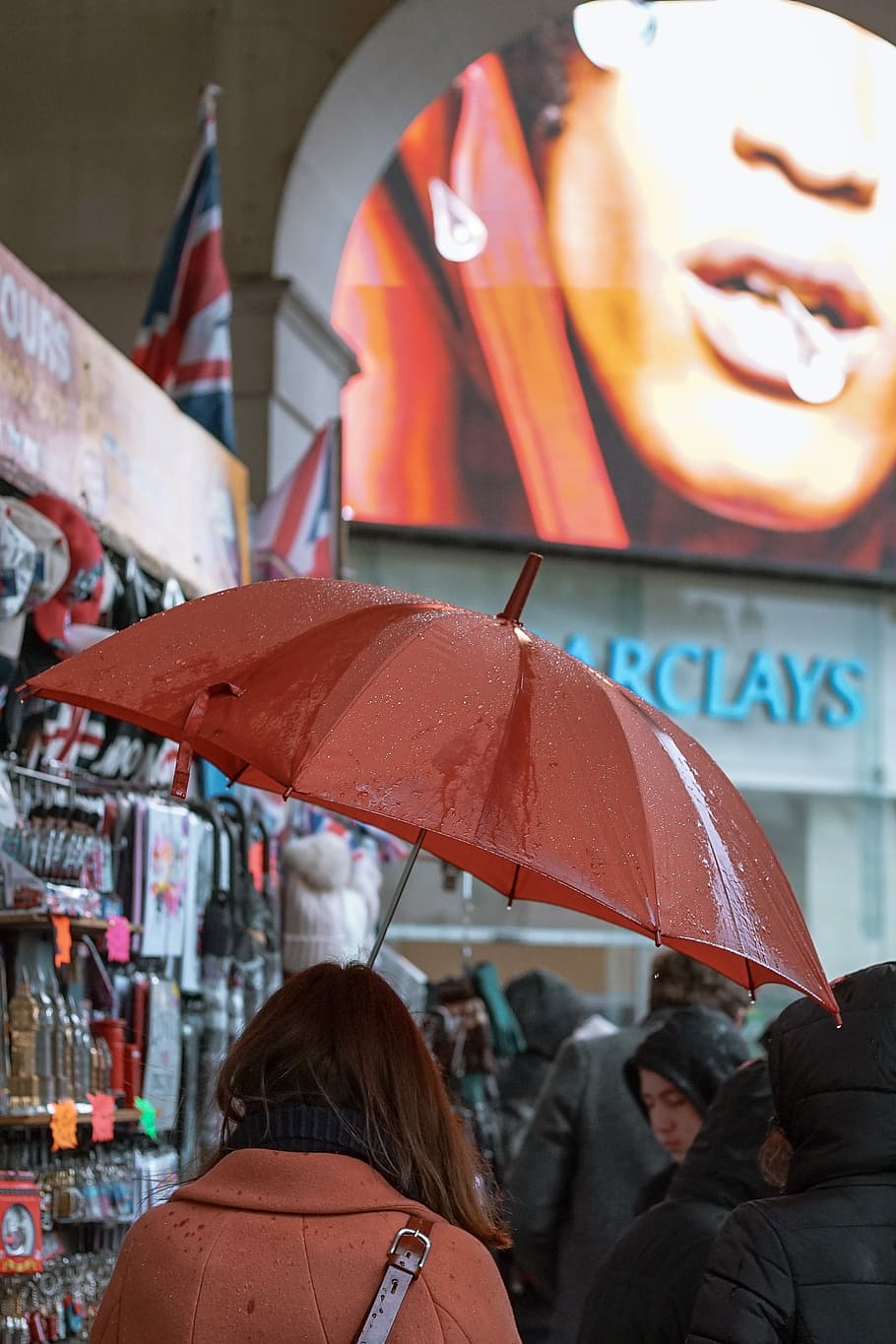 woman under wet red umbrella, woman holding umbrella inside Barclays building