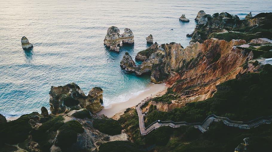 cliff near body of water with boulders, aerial photography of seashore and mountains HD wallpaper