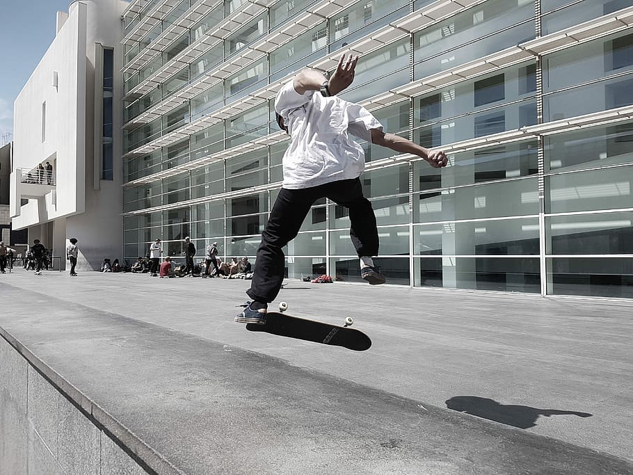 man skateboarding beside building during daytime, man jumping on skateboard in front of building, HD wallpaper