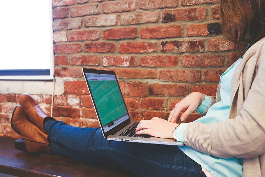 person sitting on bench facing MacBook Pro, woman, wearing HD wallpaper