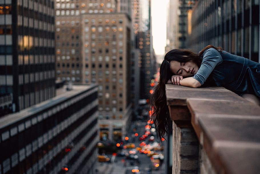 woman lying on brown building fence on the city photography during daytime HD wallpaper