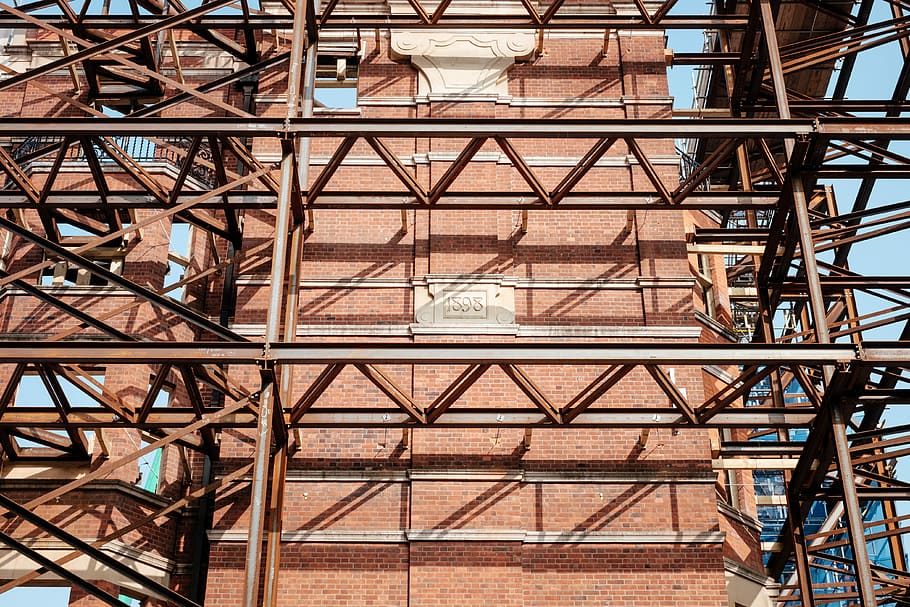 gray and red scaffolding hnear building, low angle photography of brown metal frame beside building HD wallpaper