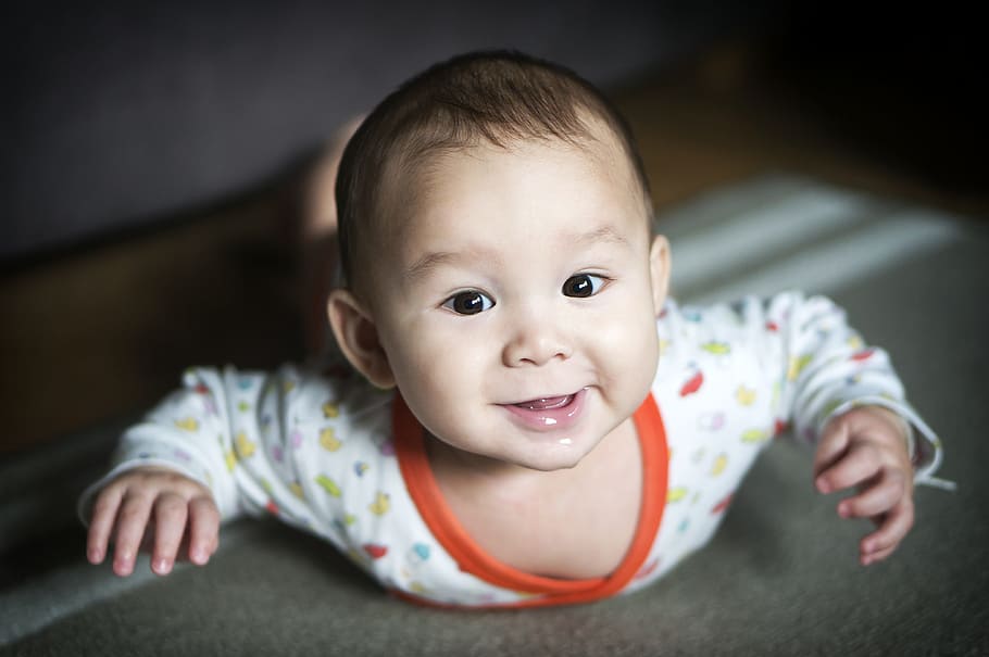 smiling baby wearing white and orange long-sleeved top, shallow focus