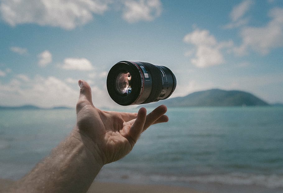 person tossing camera lens, accessory, sea, water, hands, palm HD wallpaper