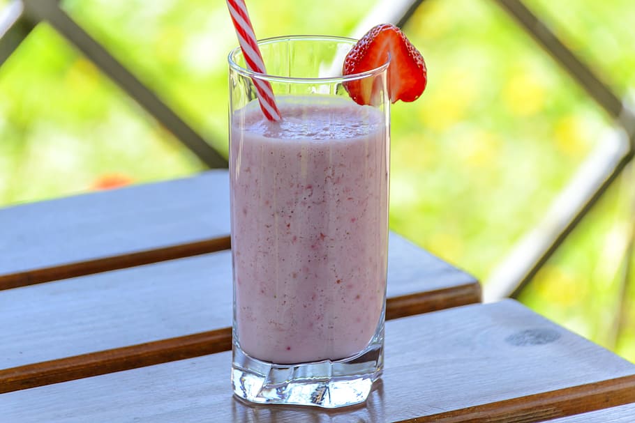 clear drinking glass with smoothies and straw, strawberry drink