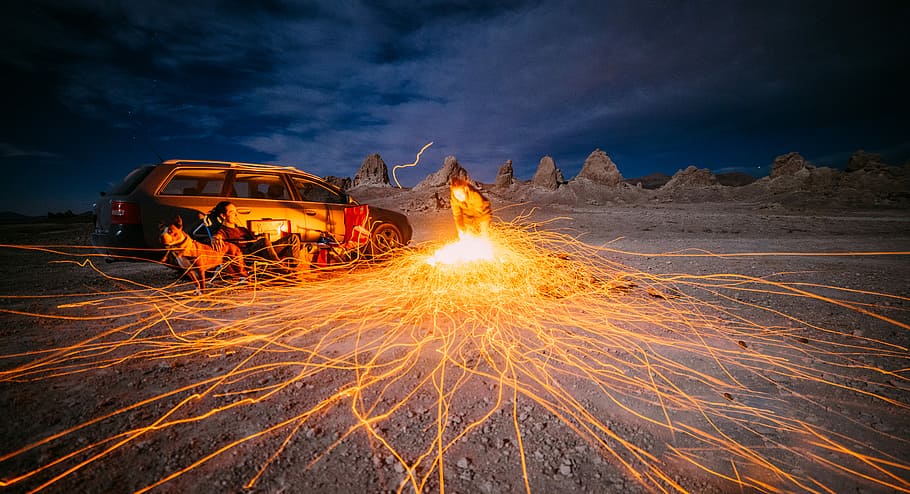 person sitting beside car under cloudy sky, time lapsed photography of a man welding in the middle of desert HD wallpaper