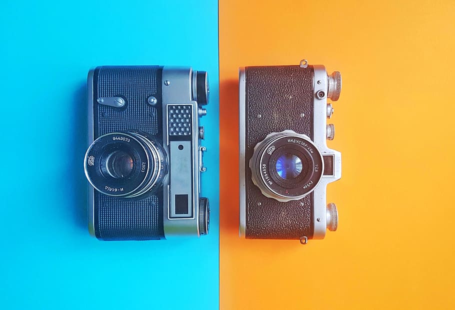 two black and grey mirrorless cameras on blue and yellow backgrounds