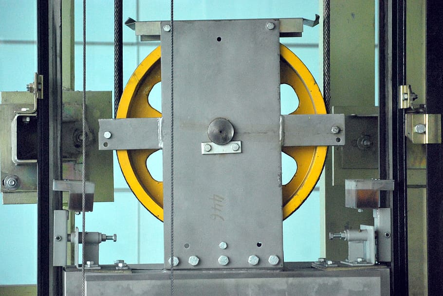 photo of yellow and grey elevator lifting mechanism, pulley, wheels
