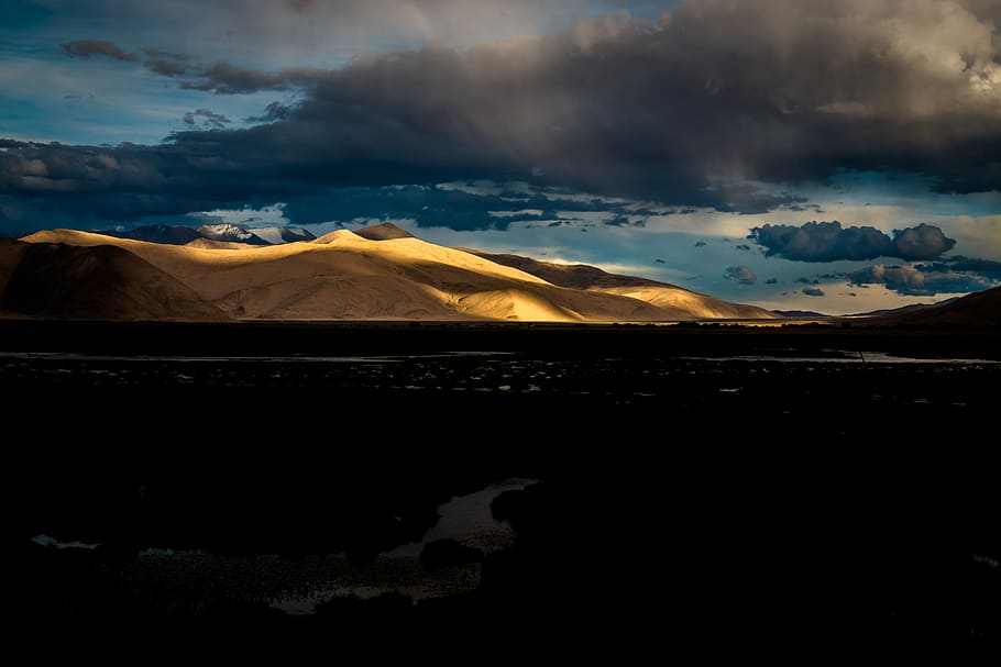 river near mountains under gray clouds, desert mountain under the cloudy sky HD wallpaper