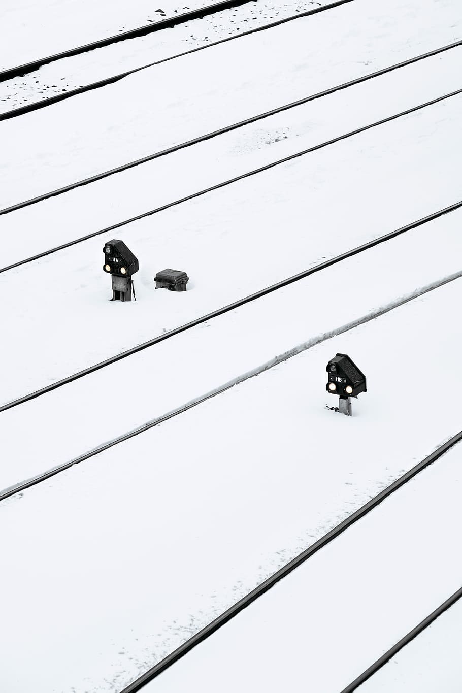 Train tracks under the heavy snow, two black-and-gray metal tools on the ground with snows