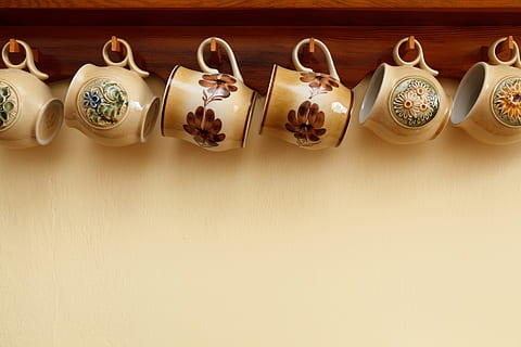 six assorted-color floral ceramic teacups hanged on brown wooden wall-mounted shelf with hooks HD wallpaper