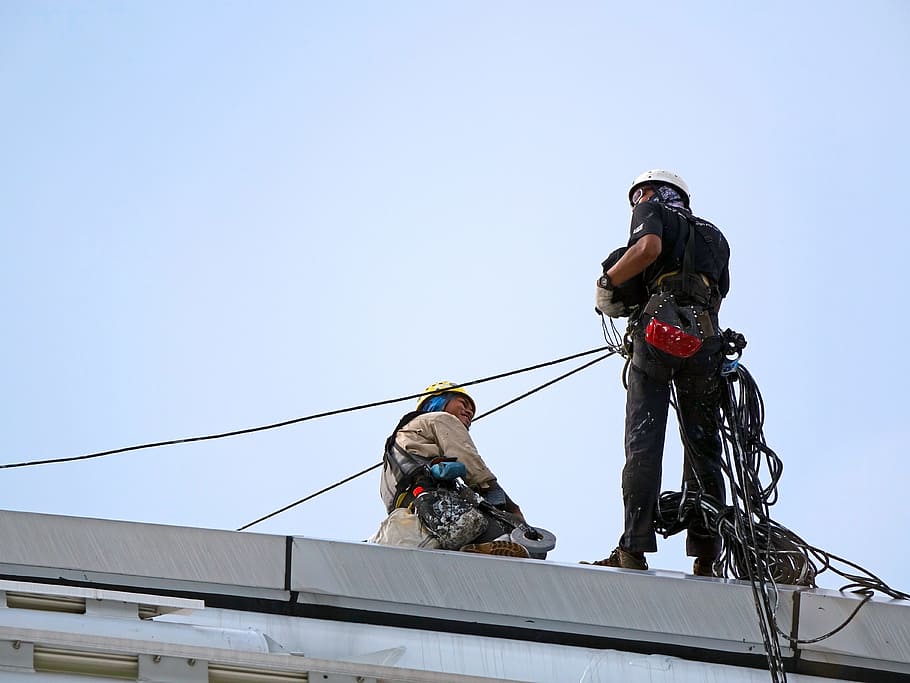 low angle photo of two men on top of gray concrete structure HD wallpaper