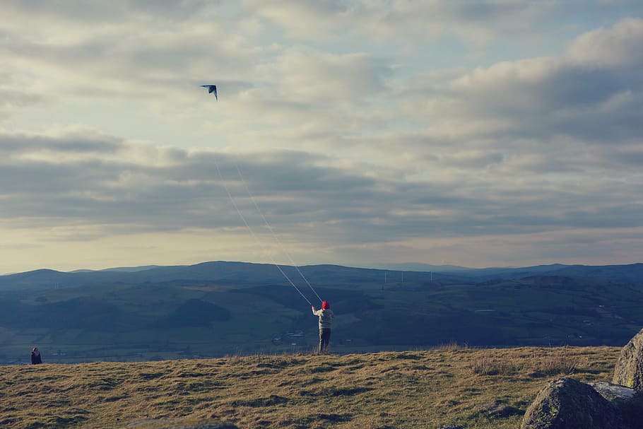 person playing with kite, flying, cloudy, sky, daytime, highland HD wallpaper