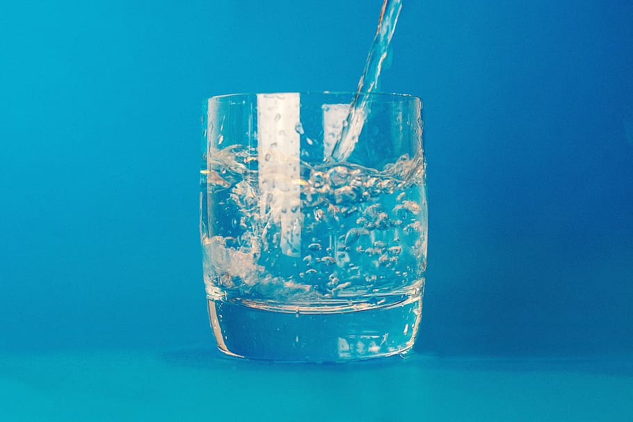 water pouring on clear glass cup, drink, blue, studio shot, colored background