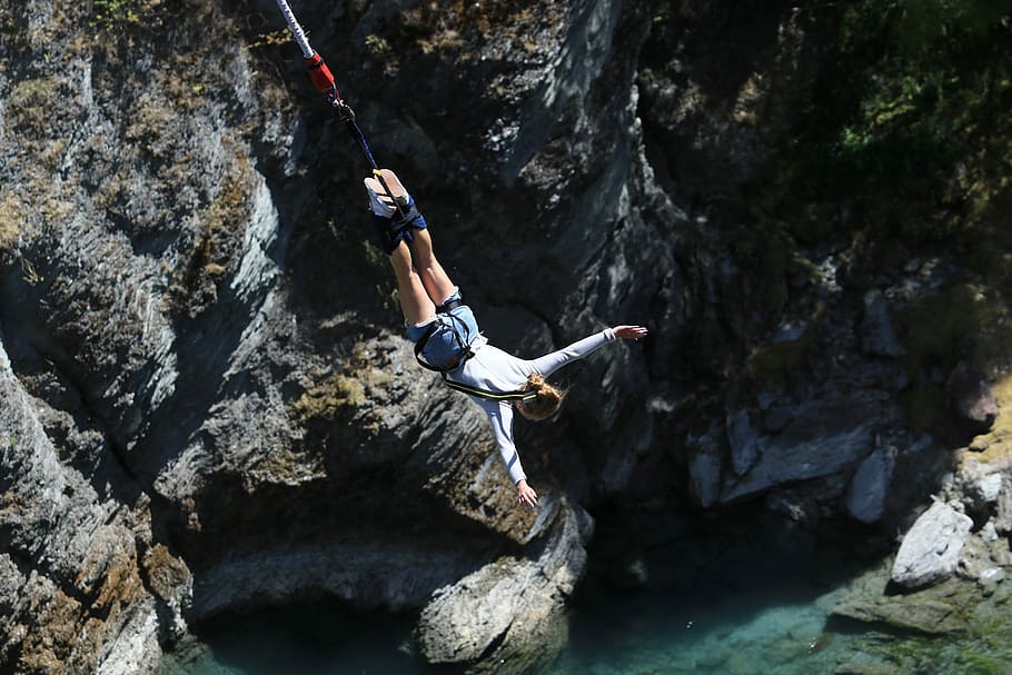 person doing bungee jumping, woman in gray long-sleeved shirt with gray denim short shorts outfit during daytime