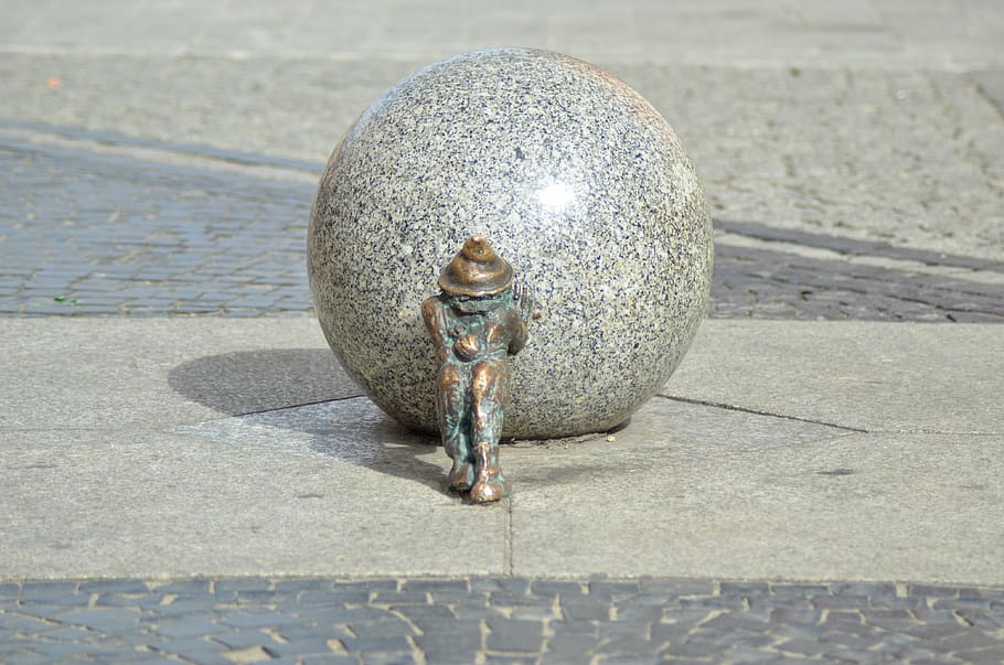 concrete ball with man pulling art work outdoors, krasnal, city