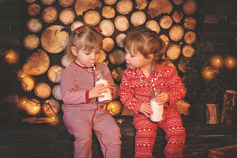 two girls wearing footie pajamas sipping drink, christmas kids