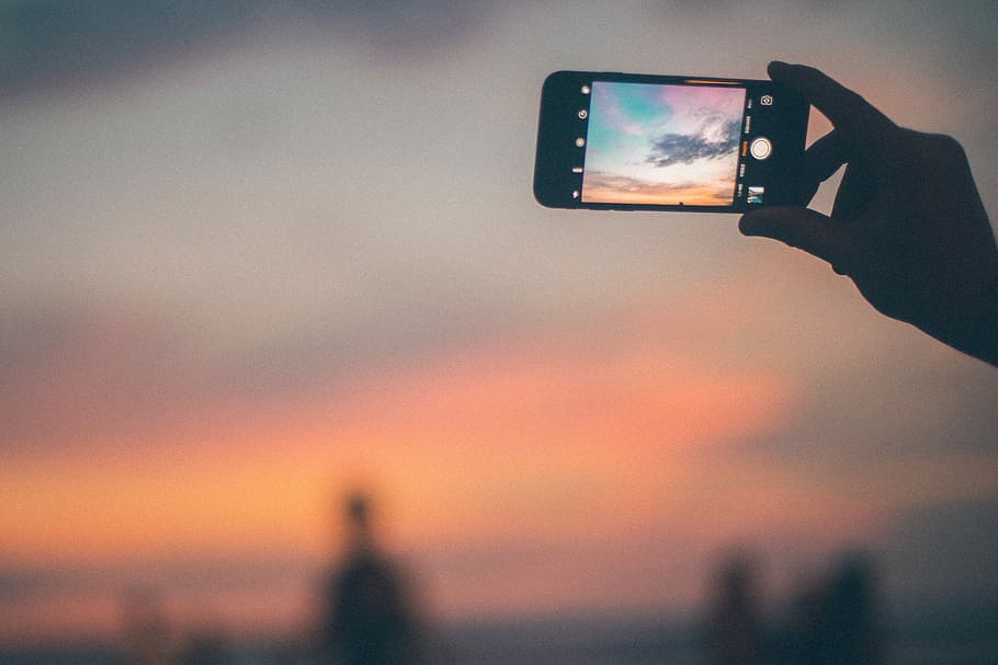 person holding black smartphone, selective focus photography of person taking photo of sky HD wallpaper