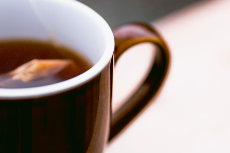 brown ceramic mug with brown liquid inside, selective focus photography of brown mug filled with tea, HD wallpaper