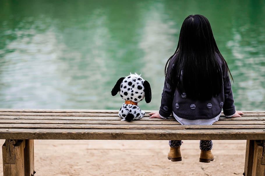 girl in black jacket and blue denim pants sitting beside dalmatian puppy plush toy during daytime, HD wallpaper