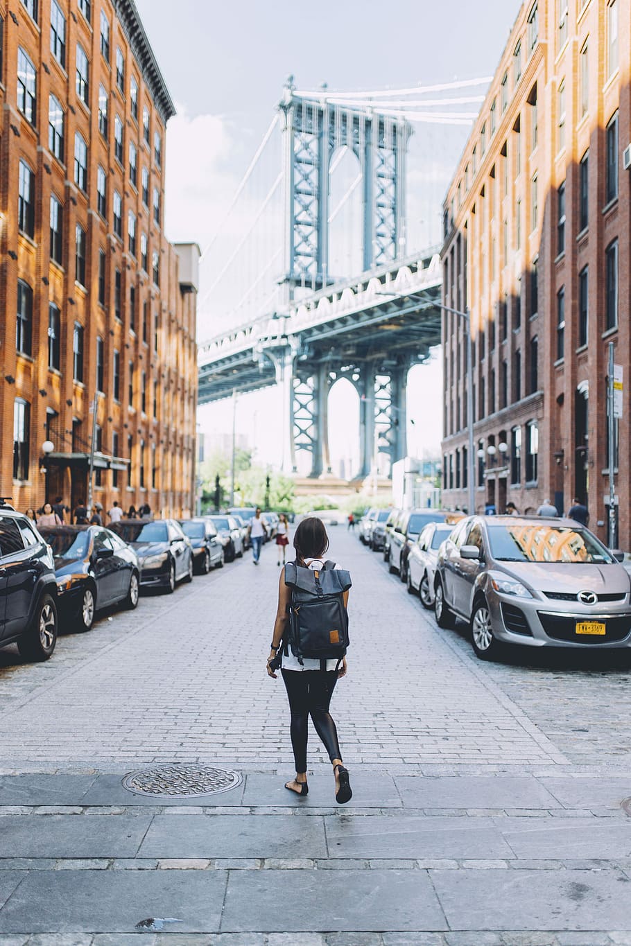woman walking on a the looking at the bridge, woman walking on road between buildings HD wallpaper