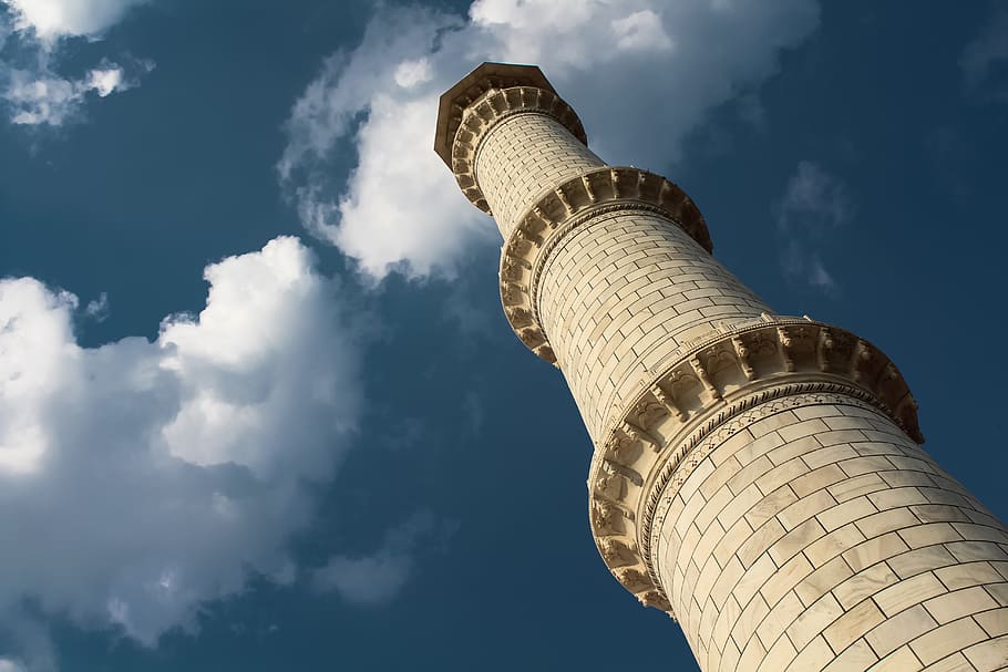 low-angle photography of beige concrete lighthouse tower under blue and white sky