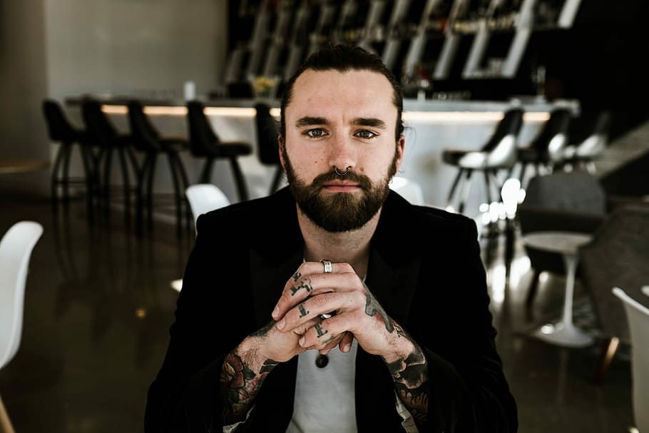 selective focus photo of man sitting on chair wearing black suit jacket HD wallpaper