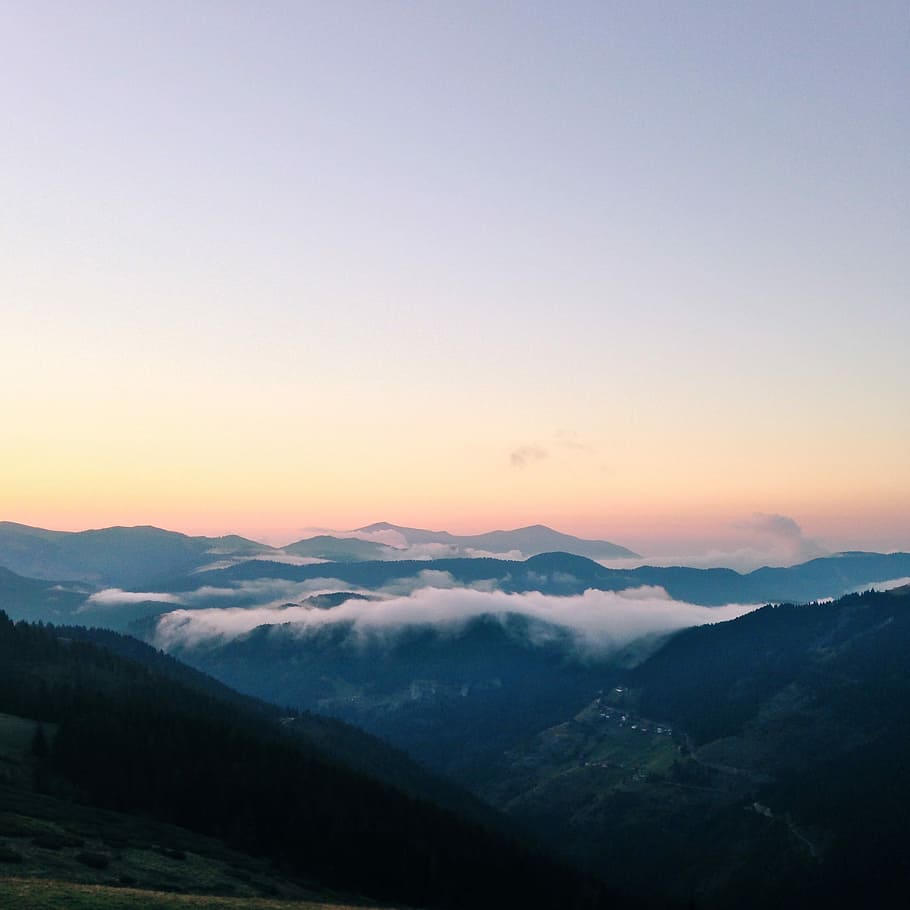 green mountains with fog during golden hour, aerial photography of mountains covered with fogs under orange and white cloudy skies HD wallpaper