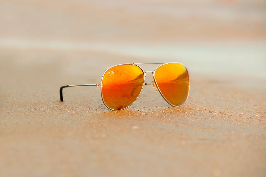 gray framed Ray-Ban orange flash lens Aviator sunglasses on brown sand