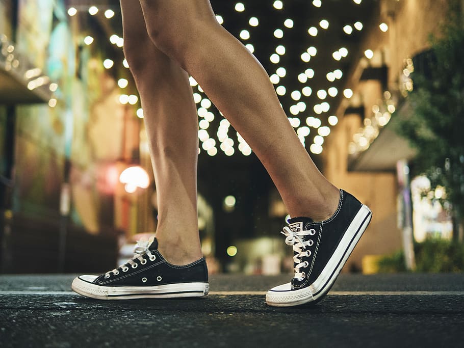 person wearing black-and-white low-top sneakers, person wearing black sneakers walking under string lights HD wallpaper