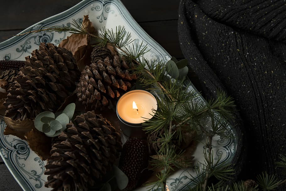 lighted candle on plate beside the pinecones, three pine cones beside tealight canlde, HD wallpaper