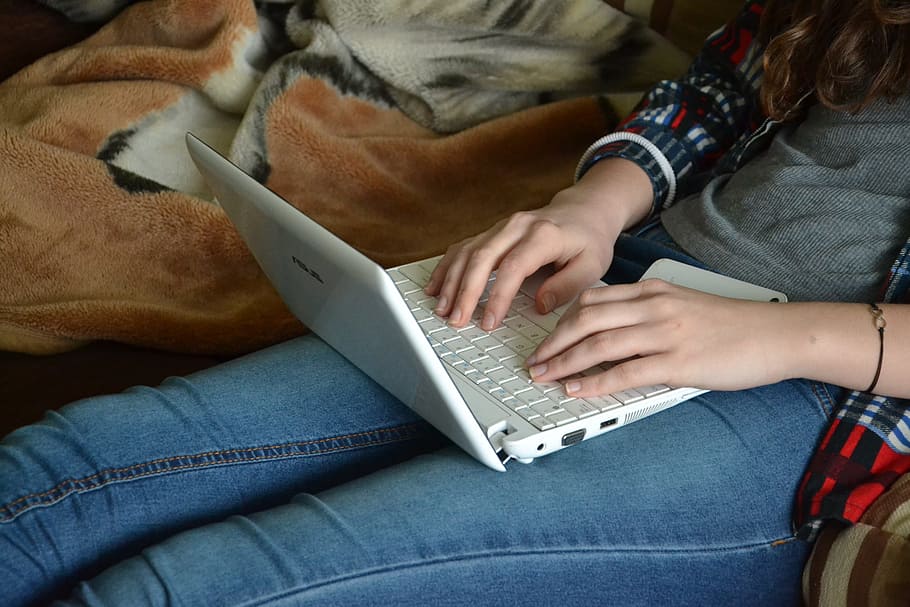 woman wearing gray long-sleeved shirt and blue jeans with white laptop on lap HD wallpaper