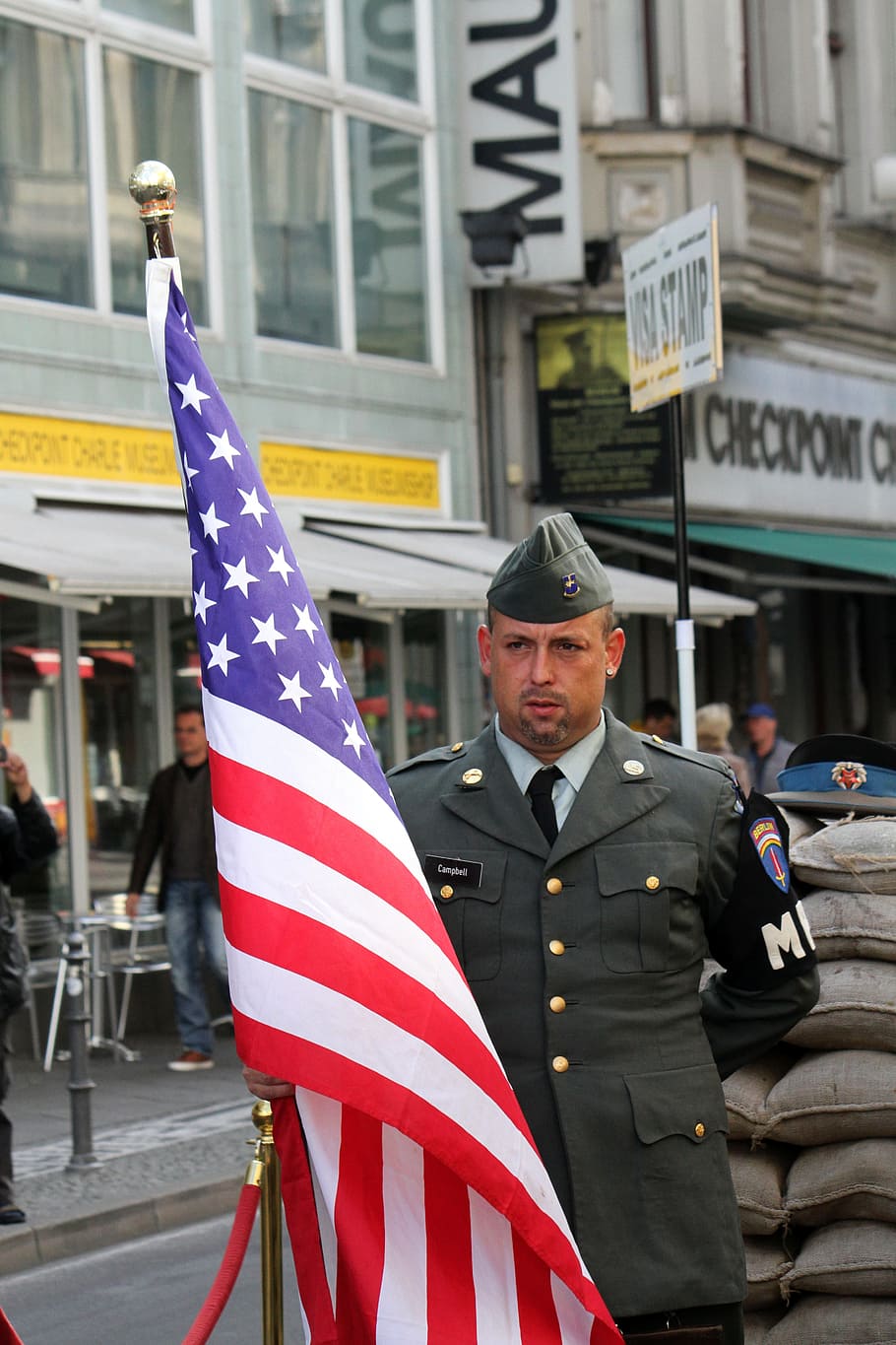 man holding USA flag near building during daytime, checkpoint