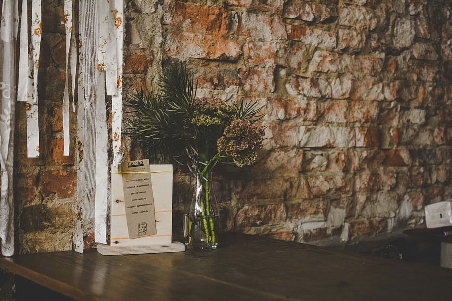 green and brown plant in clear glass vase beside brown concrete wall, clear glass vase top of table HD wallpaper